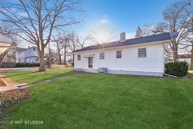 back of house featuring central air condition unit and a lawn