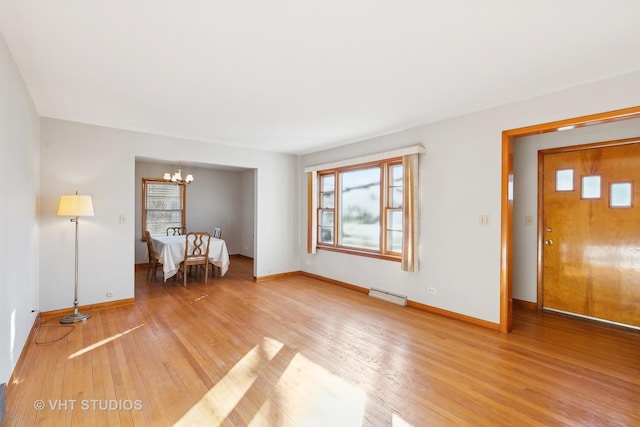 unfurnished living room featuring wood-type flooring and an inviting chandelier