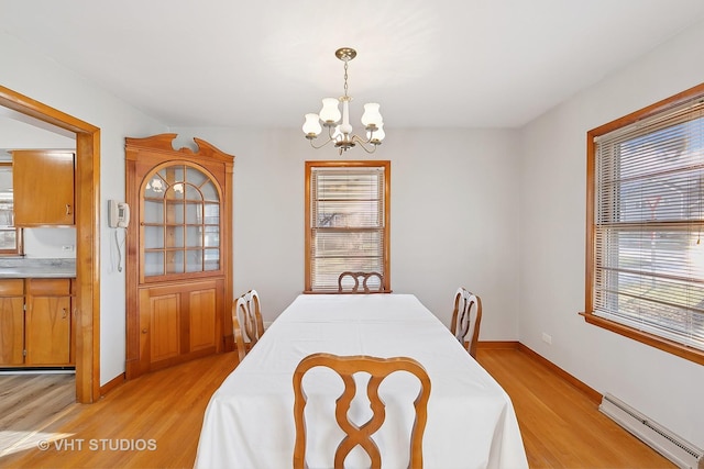 dining room featuring light hardwood / wood-style flooring, baseboard heating, and a notable chandelier