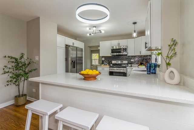 kitchen featuring white cabinets, dark hardwood / wood-style flooring, kitchen peninsula, and stainless steel appliances