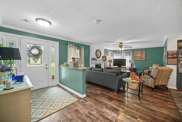 living room featuring a textured ceiling, ceiling fan, crown molding, a fireplace, and dark hardwood / wood-style floors