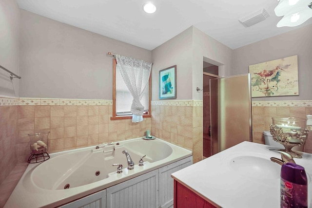 bathroom featuring vanity, shower with separate bathtub, and tile walls