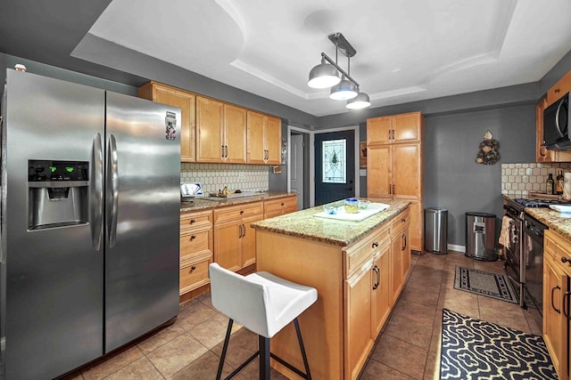 kitchen featuring a raised ceiling, pendant lighting, a center island, and black appliances