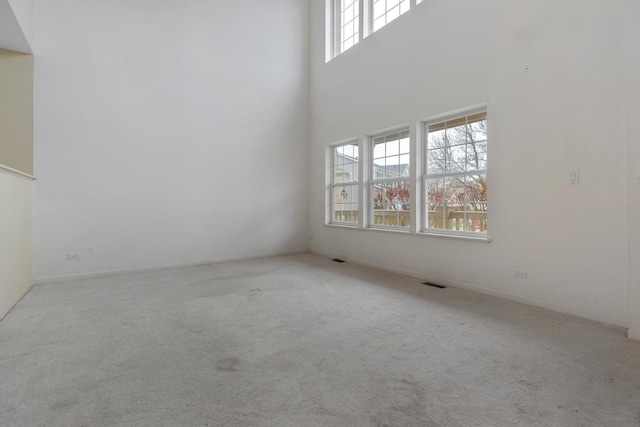 carpeted spare room with a towering ceiling