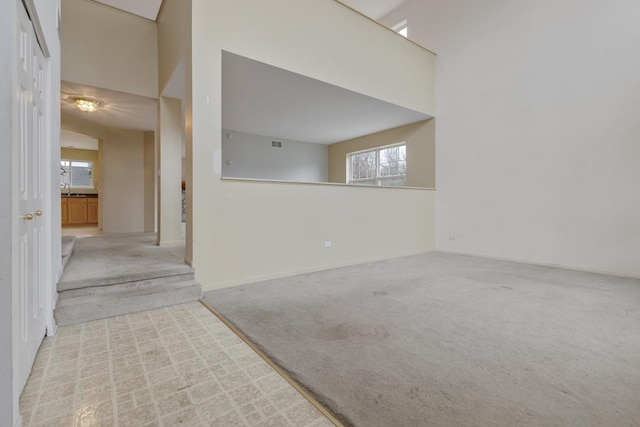 unfurnished room featuring a high ceiling, light colored carpet, and sink