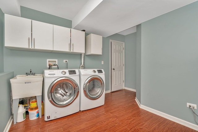 washroom featuring washing machine and clothes dryer, cabinets, and light hardwood / wood-style floors