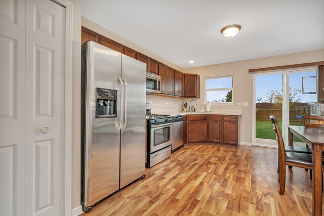 kitchen with appliances with stainless steel finishes, light hardwood / wood-style flooring, and sink