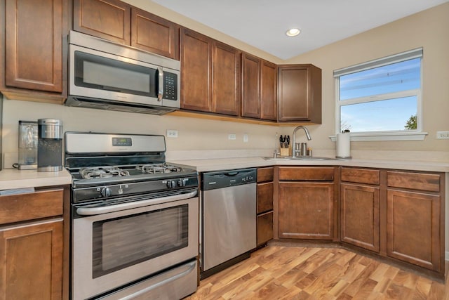 kitchen with sink, stainless steel appliances, and light wood-type flooring