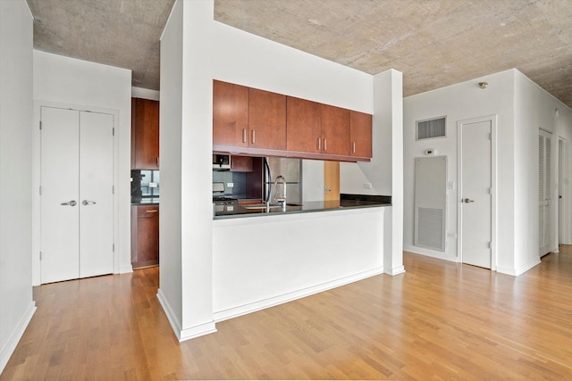 kitchen with stainless steel fridge, light wood-type flooring, and tasteful backsplash