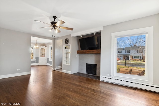 unfurnished living room with a fireplace, dark hardwood / wood-style floors, baseboard heating, and ceiling fan with notable chandelier