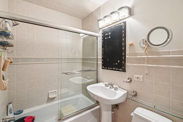 bathroom featuring toilet, tile walls, and enclosed tub / shower combo