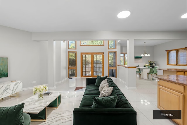 living area featuring french doors, a notable chandelier, and baseboards