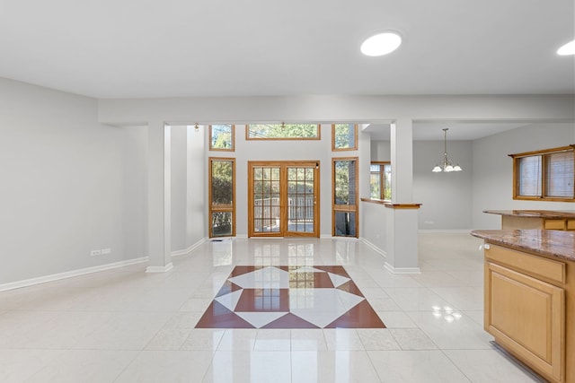 entryway with light tile patterned floors, baseboards, french doors, ornate columns, and a notable chandelier