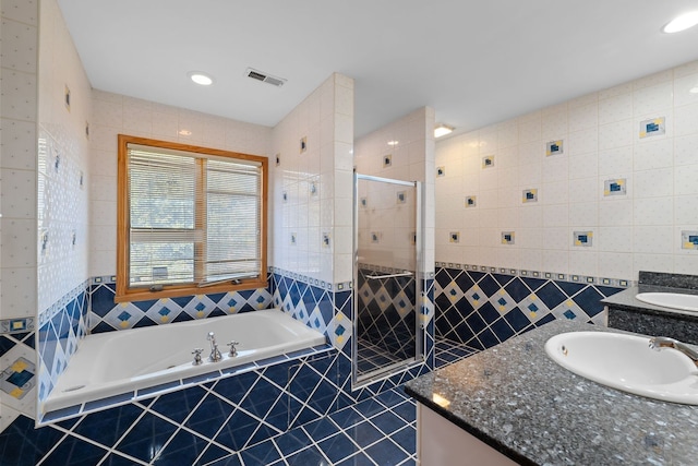 full bath featuring a stall shower, visible vents, tile walls, vanity, and a bath