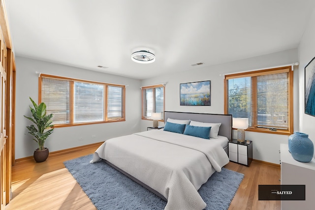 bedroom with light wood-type flooring, baseboards, and visible vents