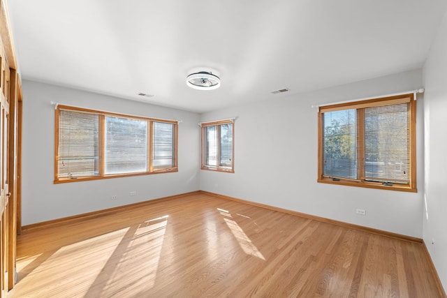 unfurnished room with light wood-style flooring, visible vents, and baseboards