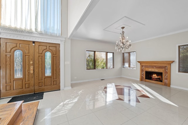 entrance foyer featuring a fireplace, crown molding, light tile patterned floors, a chandelier, and baseboards