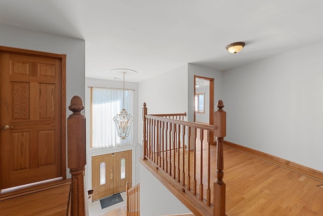 interior space with baseboards, wood finished floors, an upstairs landing, and a notable chandelier