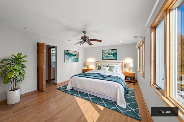 bedroom with ceiling fan, light wood-type flooring, visible vents, and baseboards