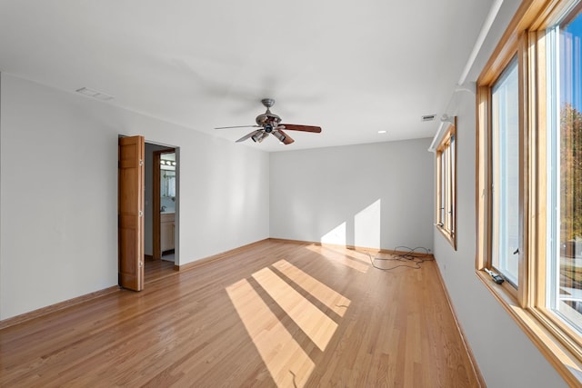 empty room featuring light wood-style floors, baseboards, visible vents, and ceiling fan