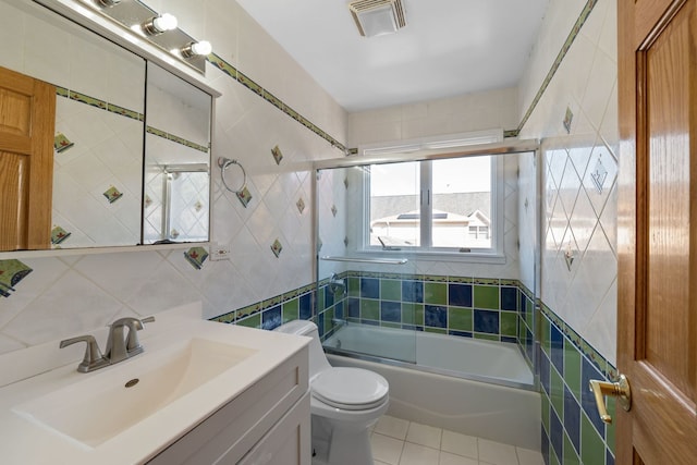 full bathroom featuring shower / bath combination with glass door, tile walls, visible vents, toilet, and tile patterned floors