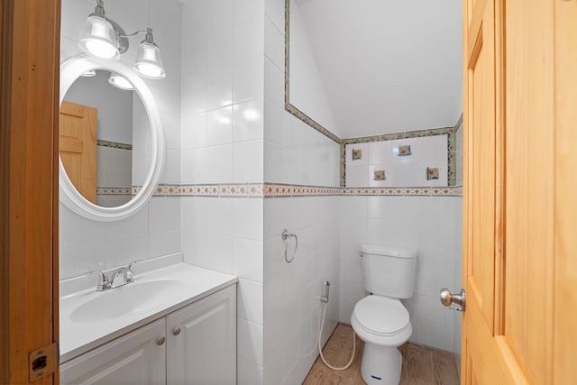 bathroom with toilet, vanity, tile walls, and lofted ceiling