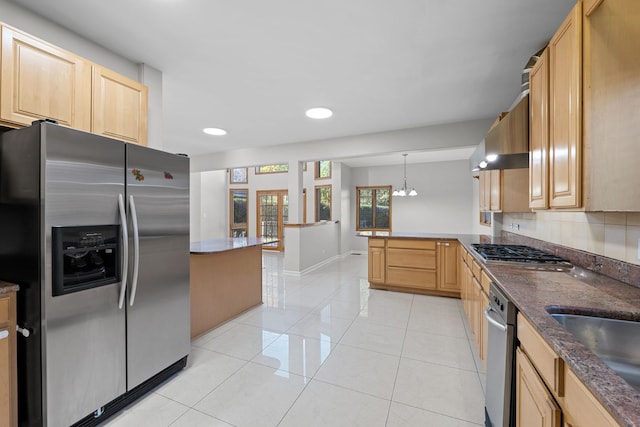 kitchen featuring light tile patterned floors, appliances with stainless steel finishes, light brown cabinets, a sink, and a peninsula