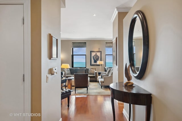 hall with light hardwood / wood-style floors and crown molding