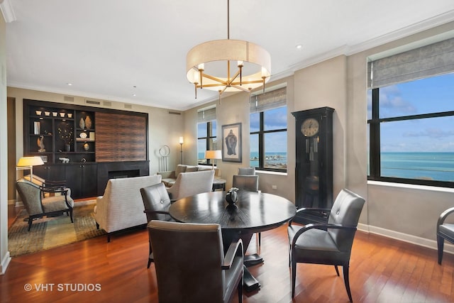 dining space with crown molding, a water view, and wood-type flooring