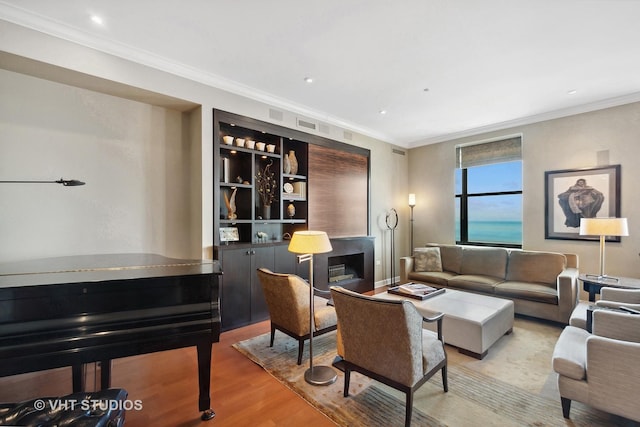 living room featuring light hardwood / wood-style floors, crown molding, and a water view