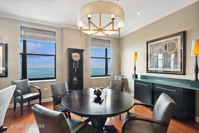 dining area with a chandelier, hardwood / wood-style floors, a water view, and ornamental molding