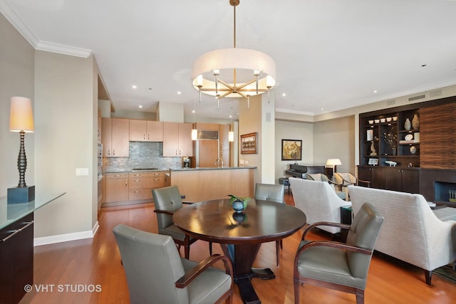 dining space with hardwood / wood-style floors, ornamental molding, and a notable chandelier