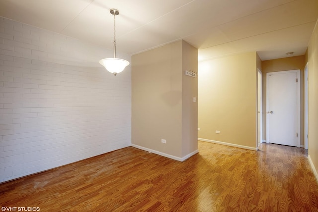 spare room with hardwood / wood-style flooring and brick wall