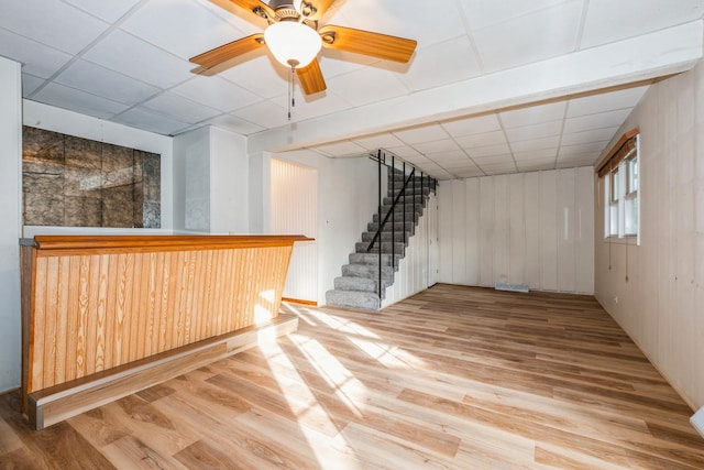 bar with a drop ceiling, light hardwood / wood-style flooring, and ceiling fan