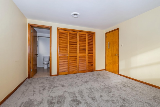 unfurnished bedroom with ensuite bathroom, a closet, and carpet flooring