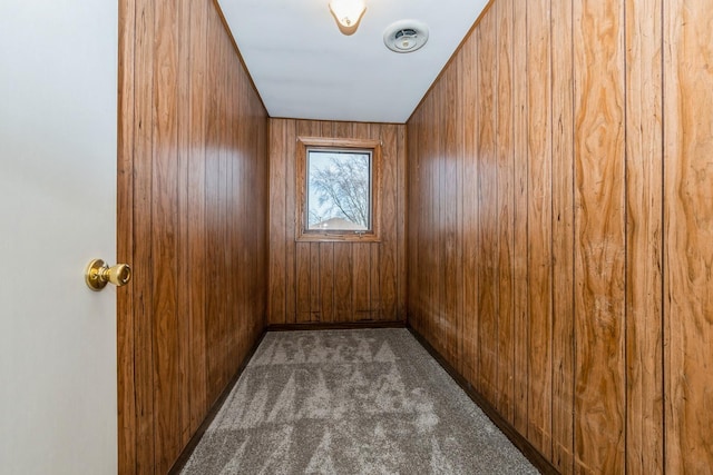 spare room featuring dark colored carpet and wood walls