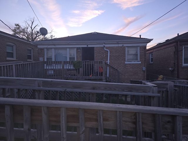 back house at dusk featuring a wooden deck