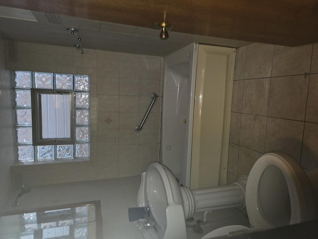 bathroom featuring tile patterned floors, tile walls, and toilet