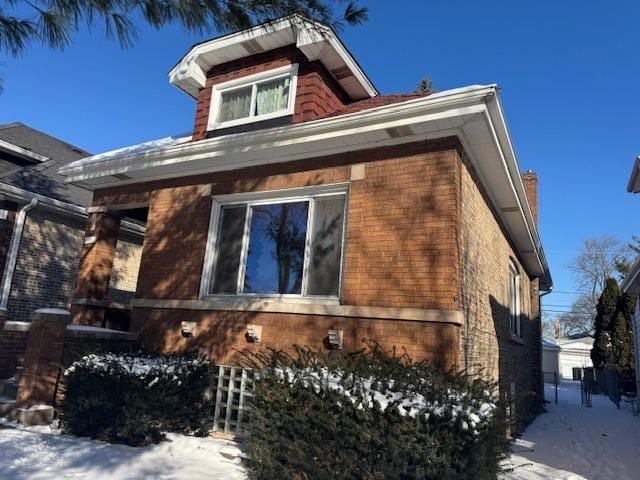 view of snowy exterior featuring brick siding