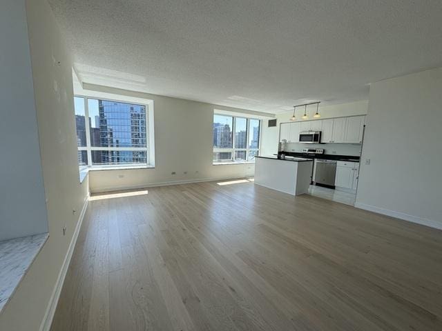 unfurnished living room featuring light wood-type flooring and a textured ceiling