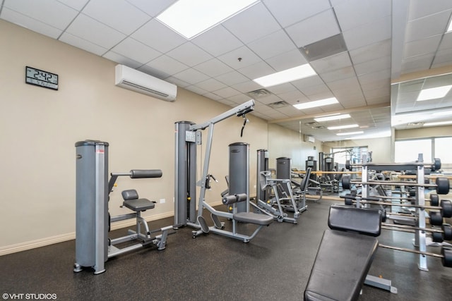 gym featuring an AC wall unit and a drop ceiling