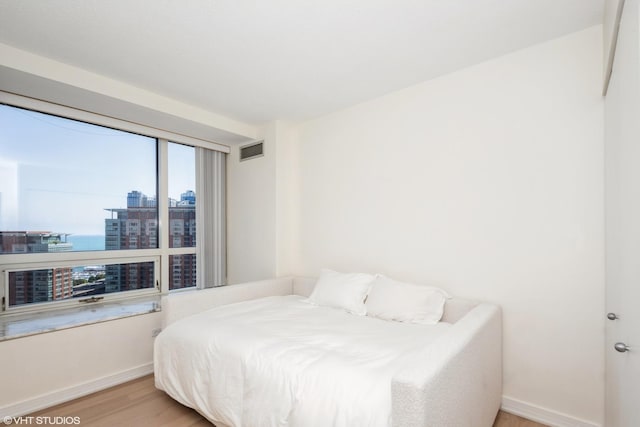 bedroom featuring hardwood / wood-style flooring and a water view