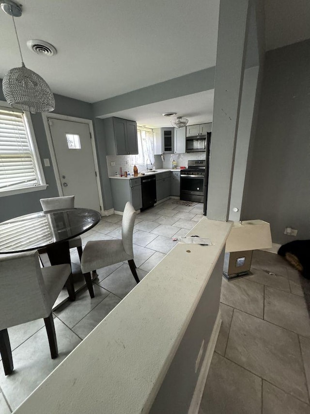 interior space featuring gray cabinetry, sink, black appliances, pendant lighting, and light tile patterned flooring