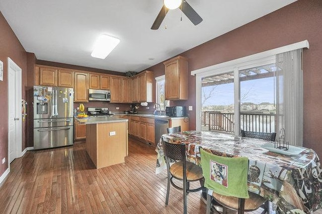 kitchen featuring appliances with stainless steel finishes, ceiling fan, sink, light hardwood / wood-style floors, and a kitchen island