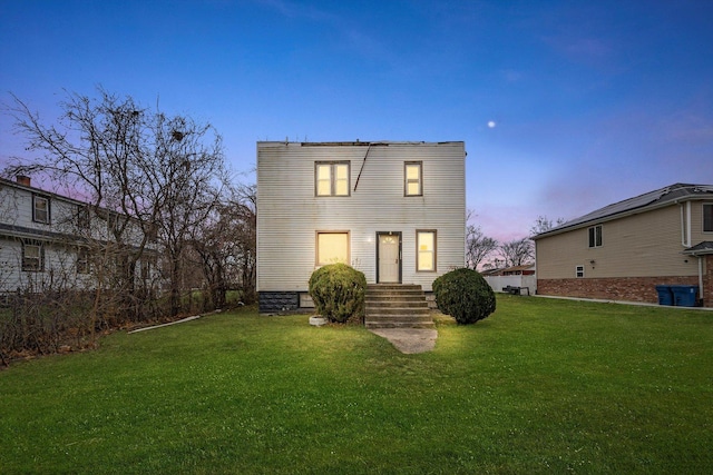 back house at dusk with a lawn