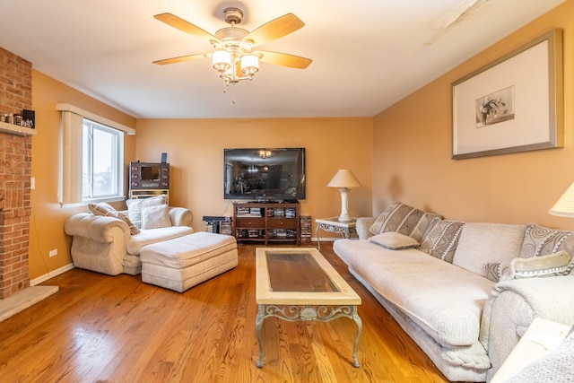 living room featuring ceiling fan, light hardwood / wood-style floors, and a brick fireplace