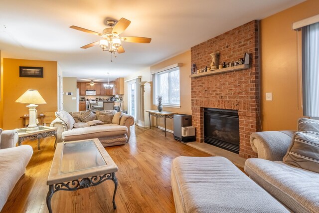 living room with ceiling fan, a fireplace, and light hardwood / wood-style flooring