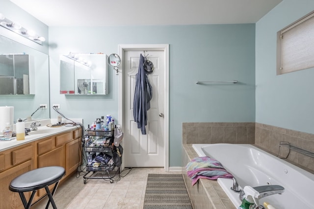 bathroom with tile patterned flooring, vanity, and tiled bath