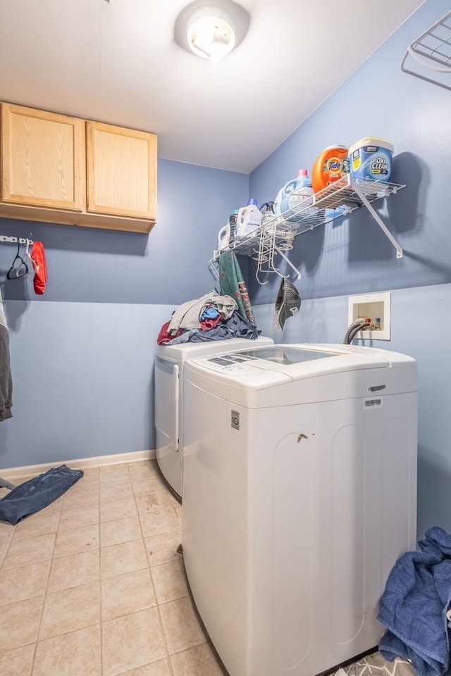 washroom with washer and clothes dryer, cabinets, and light tile patterned floors