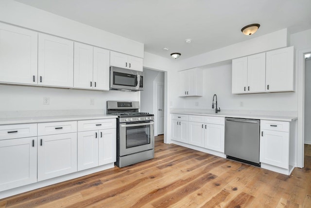 kitchen featuring white cabinetry, sink, appliances with stainless steel finishes, and light hardwood / wood-style flooring